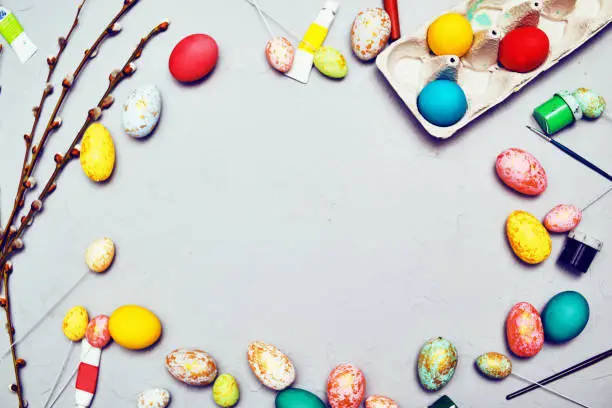 Happy easter. Colored eggs on gray concrete. Flowering, fur-seal willow, on an abstract gray background. Multicolored paints, brushes, watercolor. Space for text, empty space, flat lay.