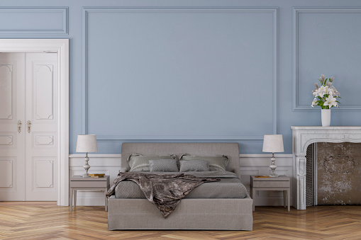 Empty glamour bedroom with decoration on hardwood floor in front of light blue antique wall with copy space, a fireplace on the right and a door on the left. Slight vintage effect added. 3D rendered image.