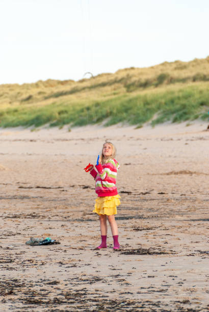 istock Young girl concentrating on flying her kite on a beach 1208341356