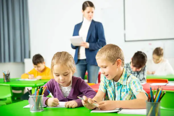 Cheerful pupils chattering while sitting at lesson in elementary school