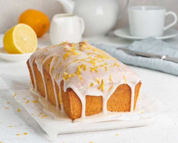 Lemon bread coated with sugar sweet. Cake with citrus, Whole loaf, side view, close up, vertical Lemon bread coated with sugar sweet icing and sprinkled with lemon peel. Cake with citrus, poppy, traditional american cuisine. Whole loaf. White background, side view, close up, vertical dessert topping stock pictures, royalty-free photos & images