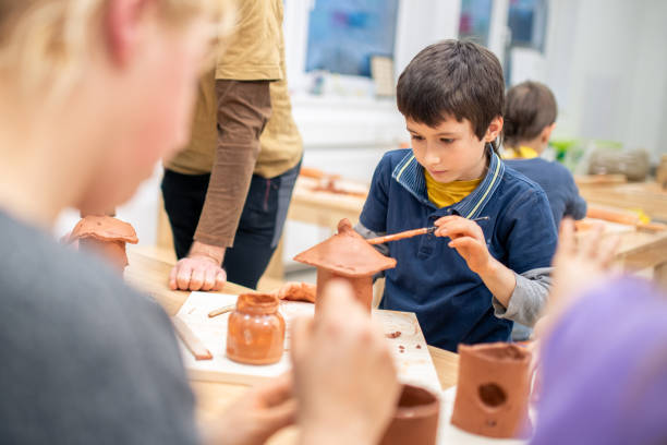 istock Schoolboy making a birdhouse from clay in class 1208346911