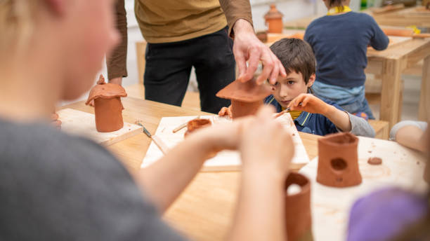 istock Teacher helping boy with clay sculpture in class 1208346916