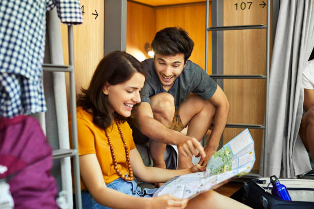 istock Happy friends discussing over map at dorm room 1208347835