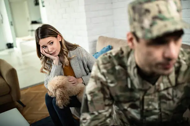 Photo of Worried woman having relationship difficulties with her military husband at home.