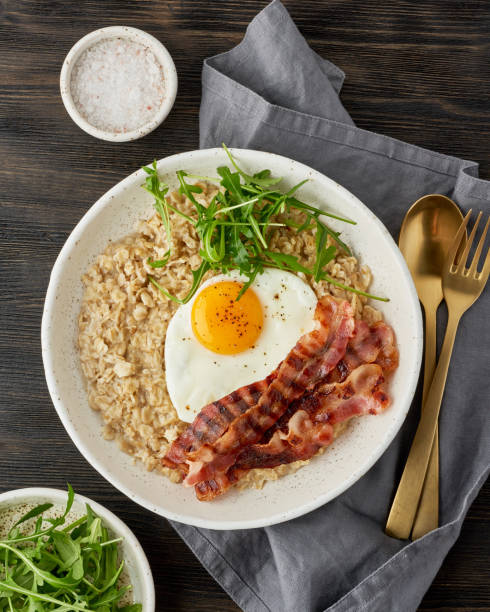 istock Oatmeal, fried egg and fried bacon. Brutal man sport protein breakfast. Balanced food. Vertical 1208349352