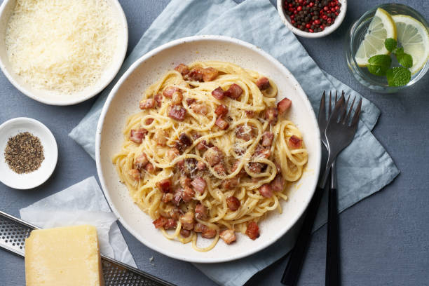 istock Carbonara pasta. Spaghetti with pancetta, egg, parmesan cheese and cream sauce. Dark gray table 1208350042
