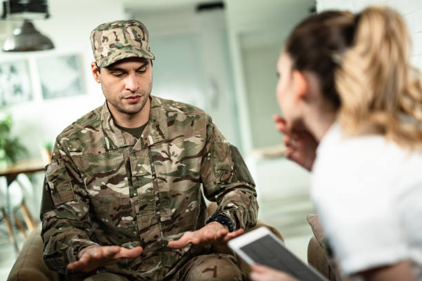 My hands are shaking all the time! Young military man gesturing while showing physiological tremor symptoms to a doctor who is visiting him at home. post traumatic stress disorder photos stock pictures, royalty-free photos & images