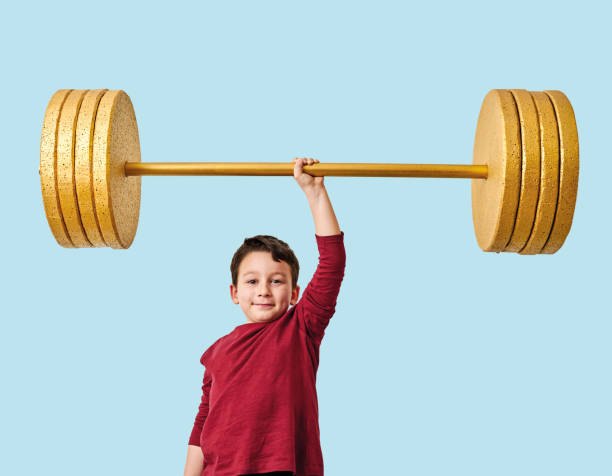 istock Cute child lifting gold barbell on blue pastel background. He is a determined and successful child. 1208352449