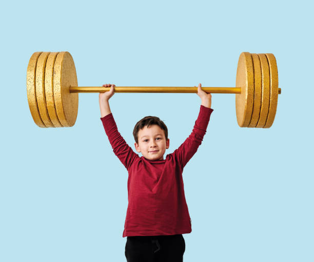 istock Cute child lifting gold barbell on blue pastel background. He is a determined and successful child. 1208352632