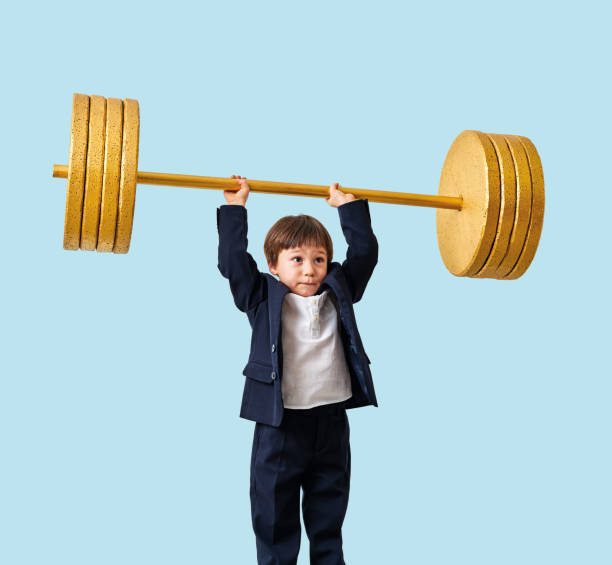 istock Cute child lifting gold barbell on blue pastel background. He is a determined and successful child. 1208352788