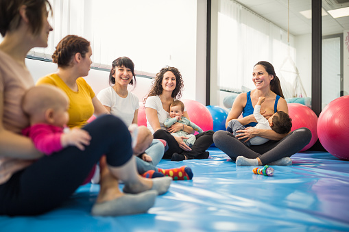 Group of mothers with their little babies on group exercise class with an instructor. Some of them breastfeeding their babies. Belgrade, Serbia