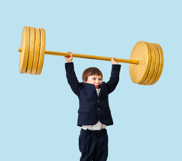 istock Cute child lifting gold barbell on blue pastel background. He is a determined and successful child. 1208352979