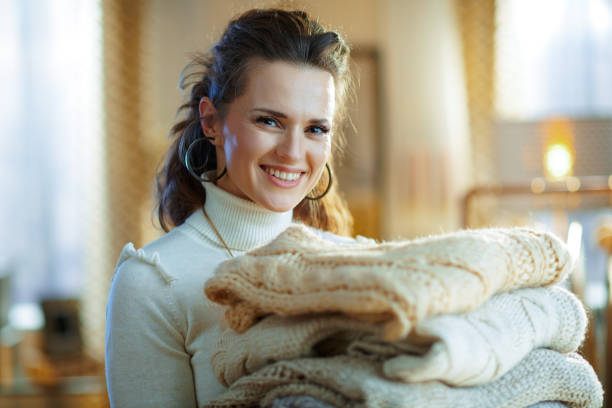 istock smiling modern middle age woman holding pile of sweaters 1208353049