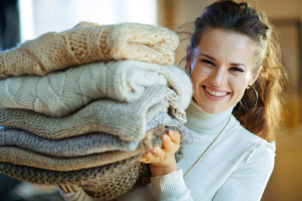 istock woman at modern home in sunny winter day holding sweaters 1208353821