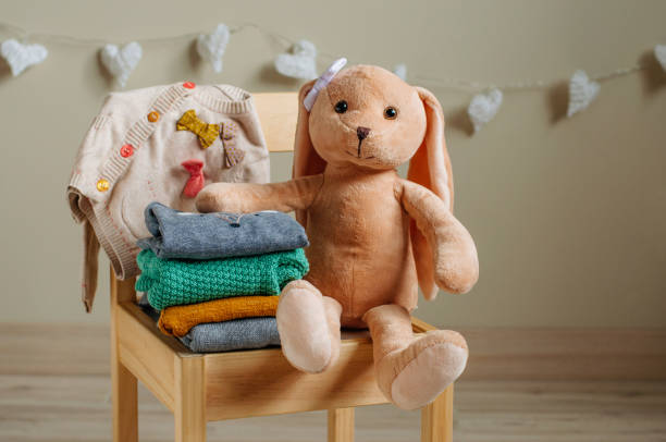abbigliamento in cotone biologico e giocattolo coniglio sulla sedia per bambini - domestic room child furniture nobody foto e immagini stock