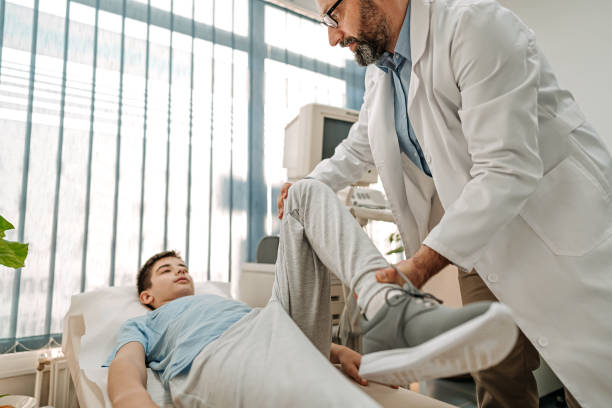 Teenage boy having his knee examined at doctor's office Teenage boy having his knee examined at doctor's office during an appointment medical examination room stock pictures, royalty-free photos & images