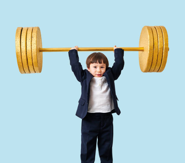 istock Cute child lifting gold barbell on blue pastel background. He is a determined and successful child. 1208354529