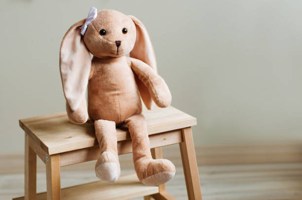 niños suave conejo de juguete con arco sentado en la silla de los niños de madera en la habitación de los niños - domestic room child furniture nobody fotografías e imágenes de stock