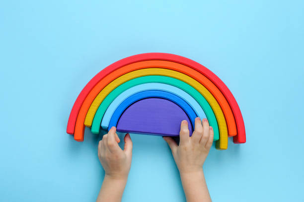 Kids hands playing with wooden toy rainbow on blue background Kids hands playing with wooden toy rainbow on blue background. Top view, flat lay. stacker stock pictures, royalty-free photos & images