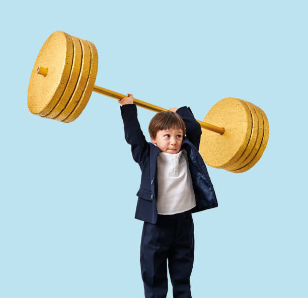 istock Cute child lifting gold barbell on blue pastel background. He is a determined and successful child. 1208354986