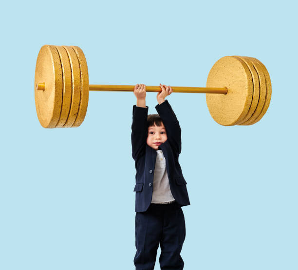 istock Cute child lifting gold barbell on blue pastel background. He is a determined and successful child. 1208355950