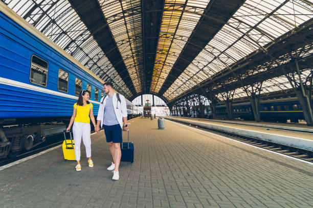 istock young couple walking by railway station with suitcases on wheels 1208357656