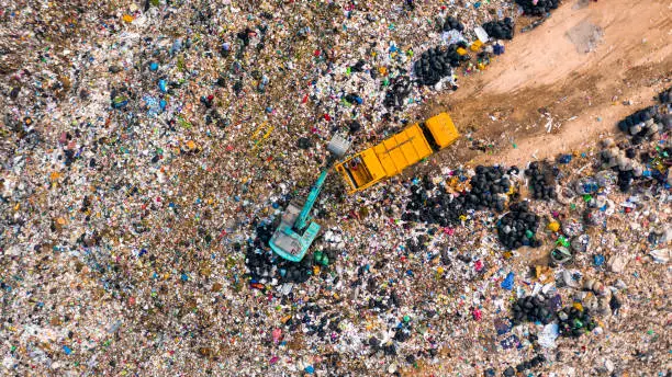 Photo of Ecosystem and healthy environment concepts and background, Garbage pile in trash dump or landfill, Aerial view garbage trucks unload garbage to a landfill, global warming.