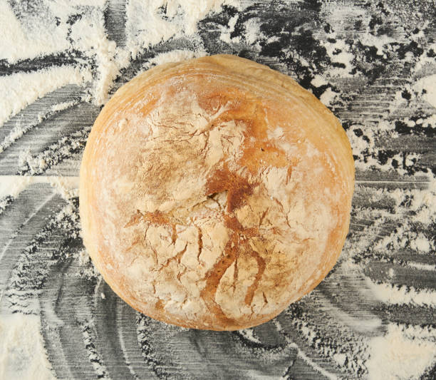 istock round baked bread and white wheat flour scattered on a black table 1208360413