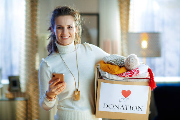 istock happy stylish woman with donation box with clothes using app 1208362391