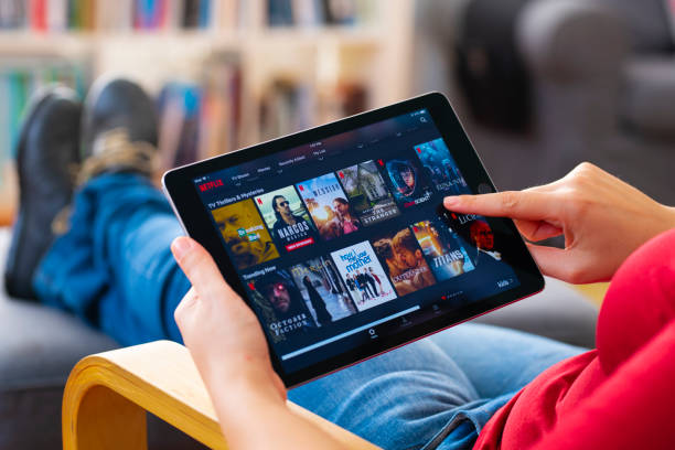 Online streaming with tablet pc İstanbul, Turkey - July 1 2018: Woman using tablet computer and looking an online streaming platform. The tablet pc is an iPad Air 2, developed by Apple Inc. keep an eye on stock pictures, royalty-free photos & images