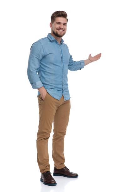 istock Smiling casual man presenting with his hand in his pocket 1208364745