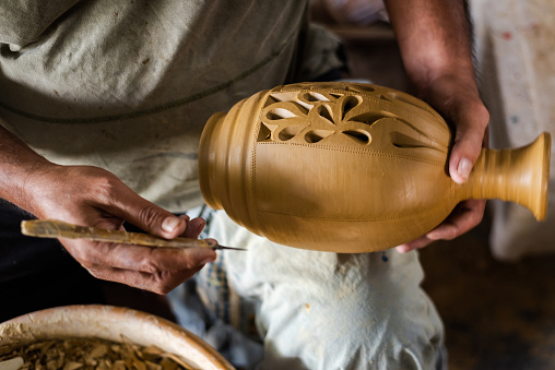 Hands of a potter, creating an earthen jar on the circle.