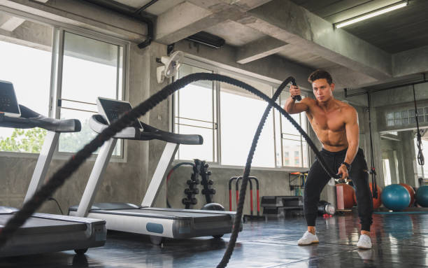istock Young man working out with battle ropes at gym. 1208365191