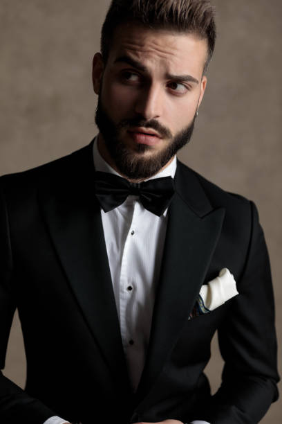 istock Charming groom looking away curiously while wearing tuxedo 1208366650