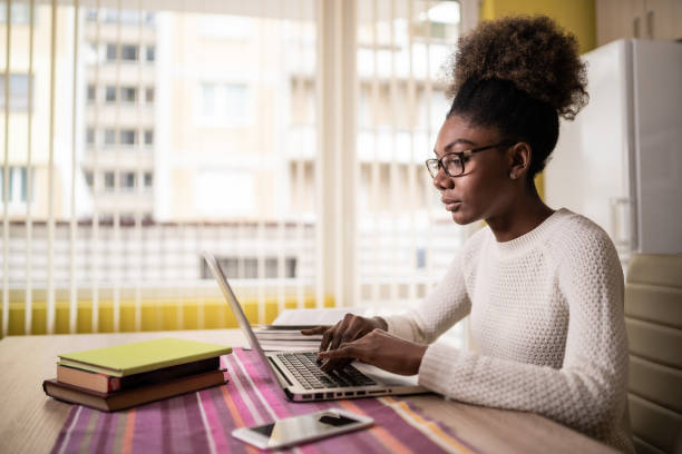 istock Afro Woman sitting at home using laptop and studying 1208367355