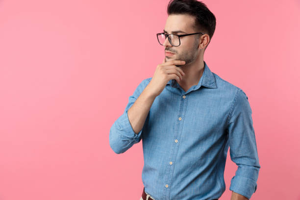 istock thoughtful young guy holding hand to chin and thinking 1208368317