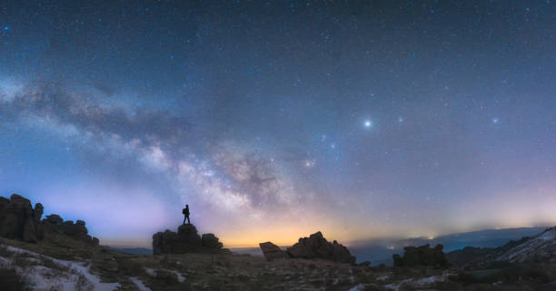 un hombre de pie junto a la galaxia de la vía láctea - constelación fotos fotografías e imágenes de stock