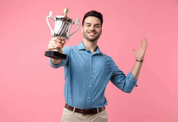 istock young happy guy smiling and holding trophy 1208372063