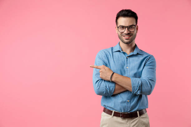 istock happy young guy pointing finger to side and smiling 1208372115