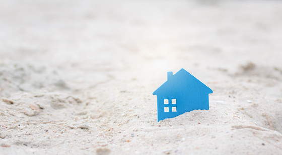 Real estate investment with Small home on sand. New house property model on the beach with a holiday. copy space used for add messages.