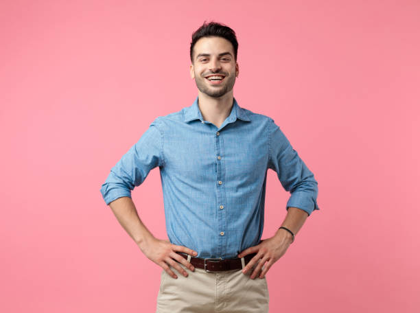 istock happy young casual guy smiling and holding hands on hips 1208372994