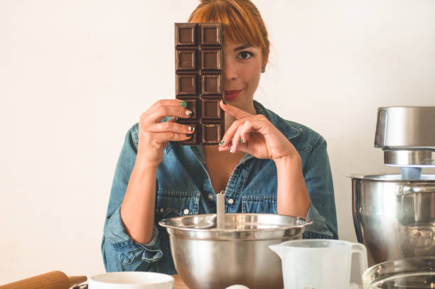 istock Confectioner redhead girl holds chocolate while covering her face. Concept ingredients for cooking flour products or dessert 1208373003