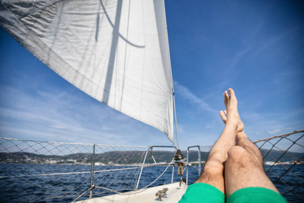 relaxing pov point of view: man crossed legs on a yacht sailing boat during cruise - onboard camera imagens e fotografias de stock