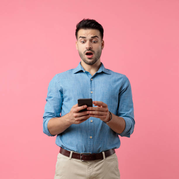 istock surprised casual guy holding phone and reading news 1208374514
