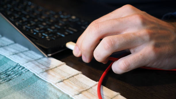 homem caucasiano carregando um laptop aberto com um carregador portátil - alenka - fotografias e filmes do acervo