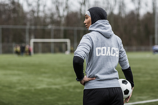 Beautiful Young Female Athlete wearing a sports hijab on at an outdoor football sporting complex as a soccer coach