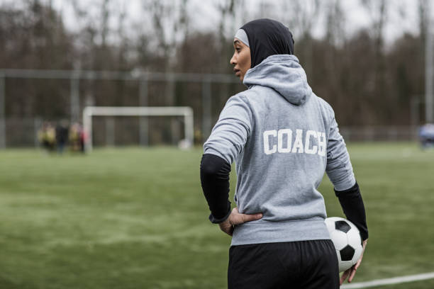 Beautiful Young Female Muslim Soccer Coach Beautiful Young Female Athlete wearing a sports hijab on at an outdoor football sporting complex as a soccer coach coach stock pictures, royalty-free photos & images