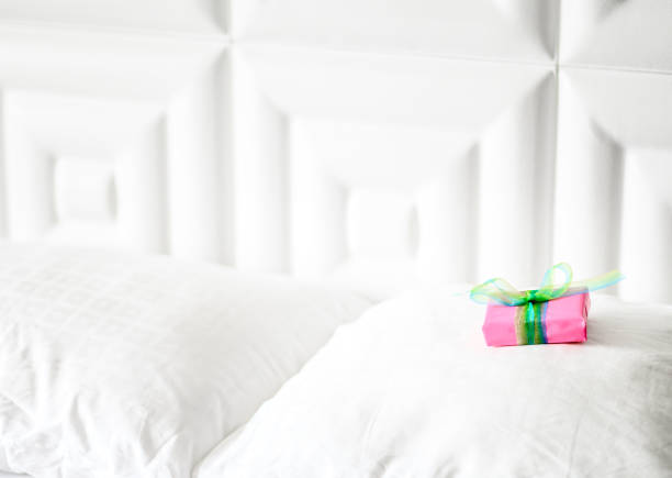 istock Special wrapped gift placed on a clean white bed, surprise present 1208378717