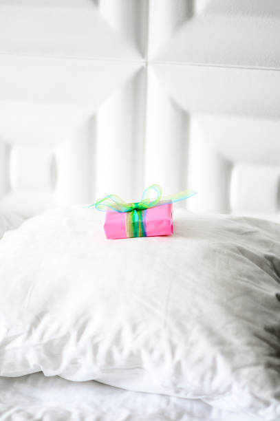 istock Special wrapped gift placed on a clean white bed, surprise present 1208378915